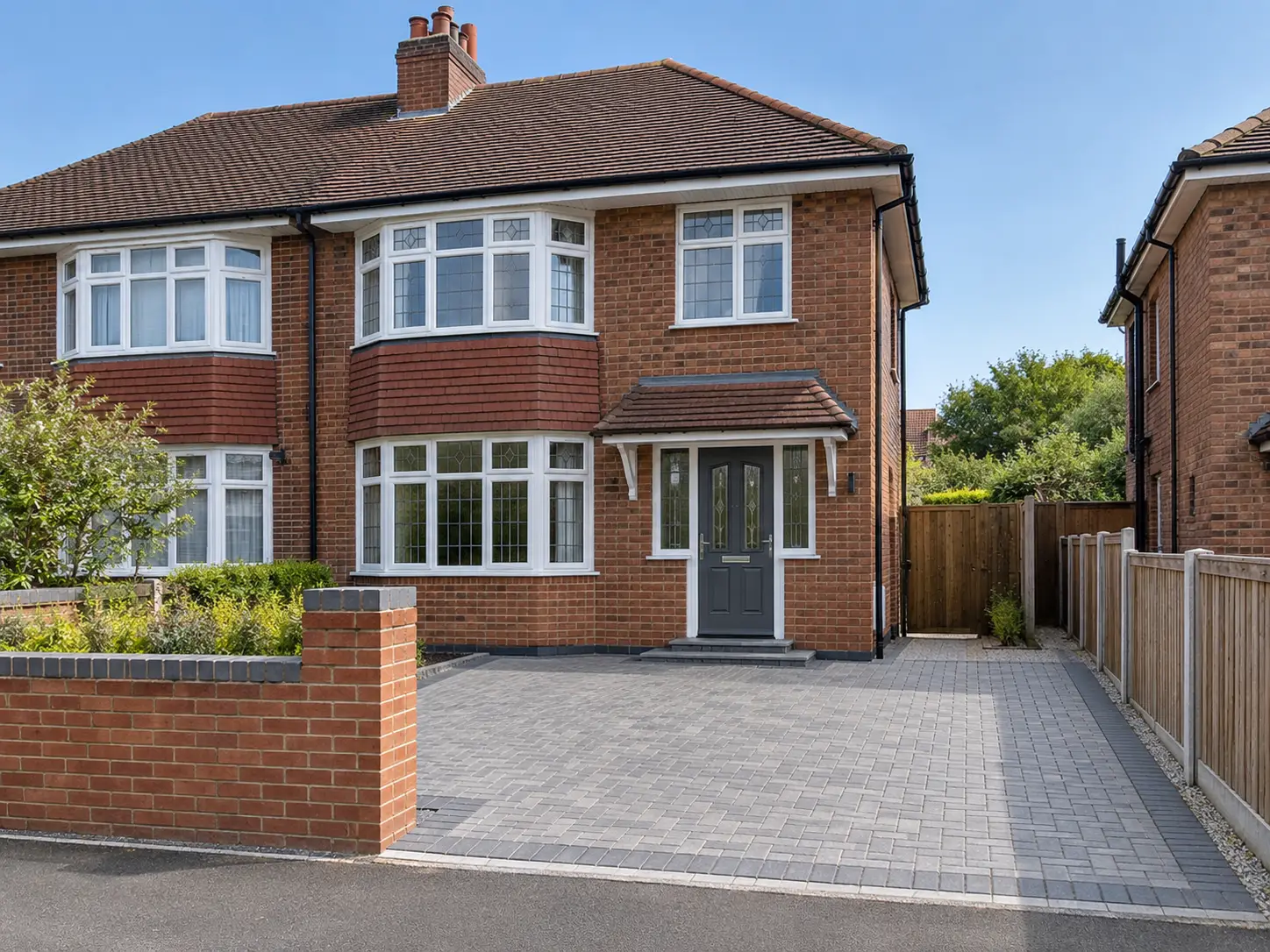 1930s brick semi-detached house with a new grey block-paved driveway and a new low brick front wall
